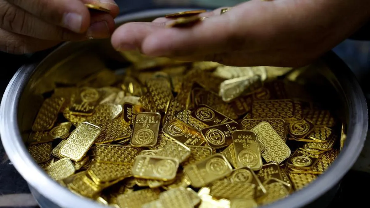 An Egyptian jeweller displays gold bars during a market interview.