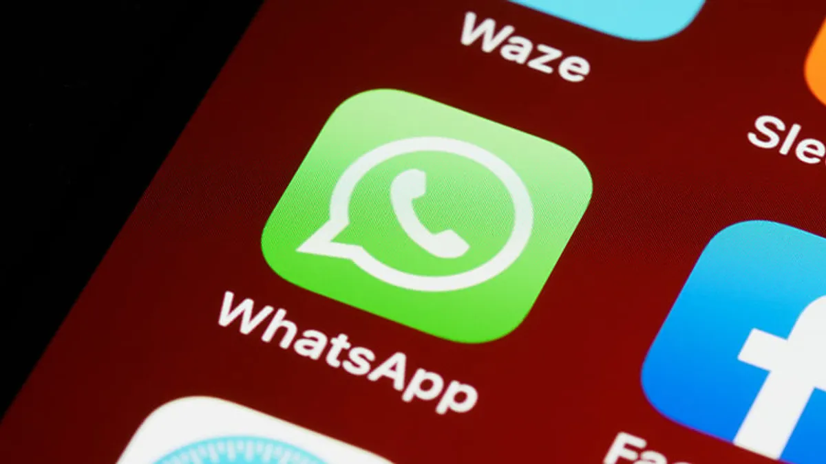 A user holding an older iPhone with a WhatsApp notification.
